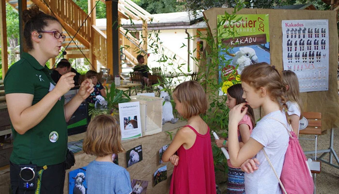 Eine Mitarbeiterin des Tierparks kl&auml;rt eine Gruppe Sch&uuml;lerinnen zum Thema Artenschutz auf